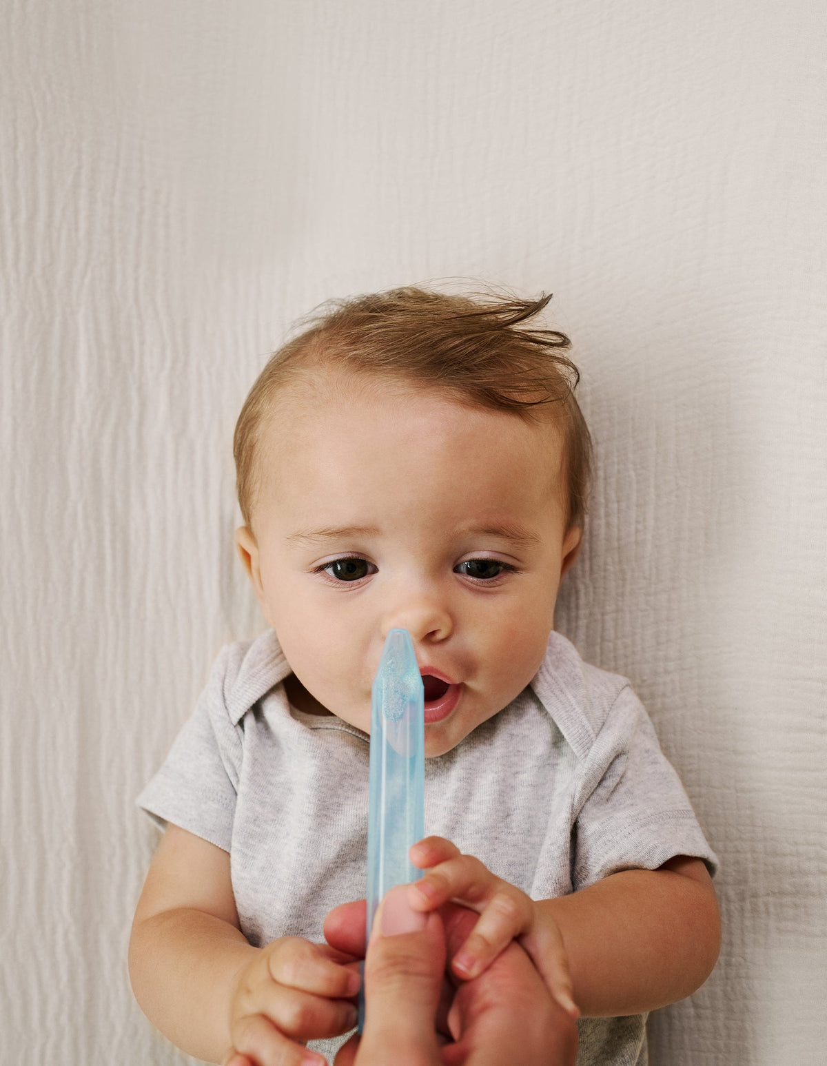 Parent using the NoseFrida nasal aspirator on a baby